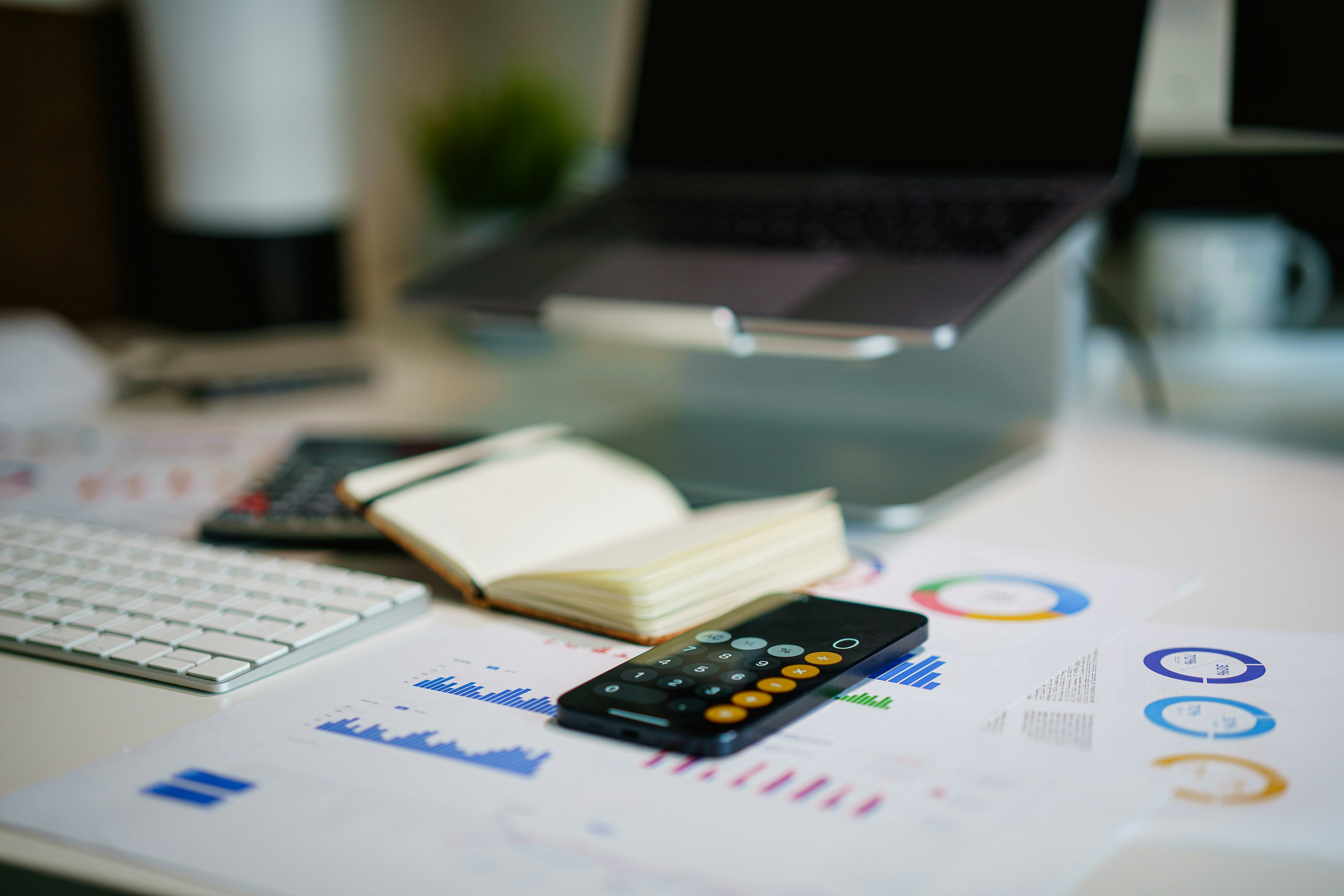 Desk with financial charts, calculator and laptop